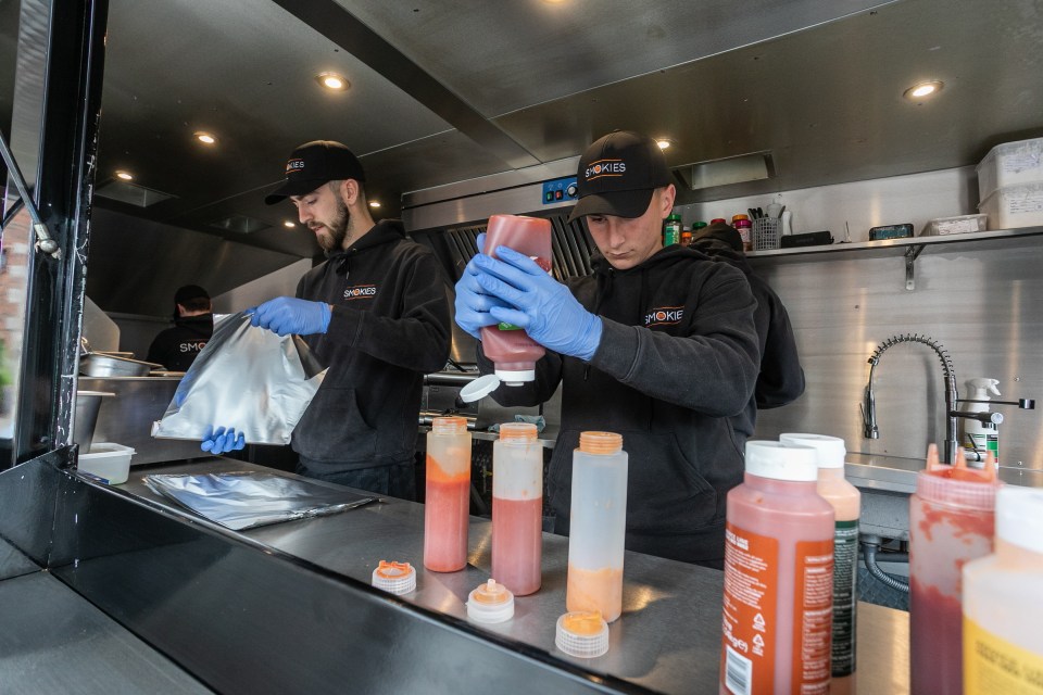Two employees of a smash burger van prepare sauces.