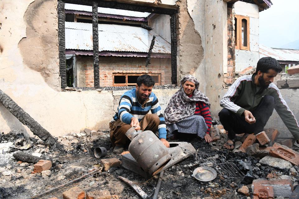 A family surveys the damage to their home after shelling.