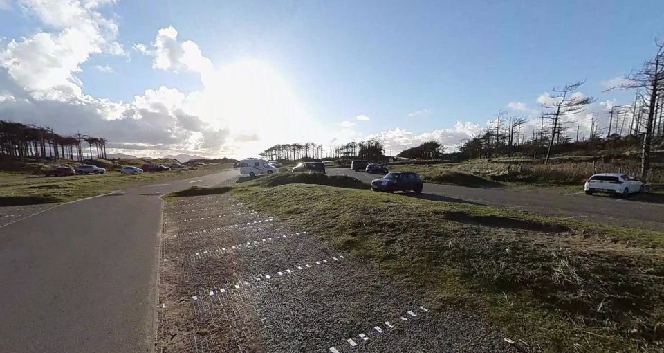 Newborough beach parking lot with several cars parked.