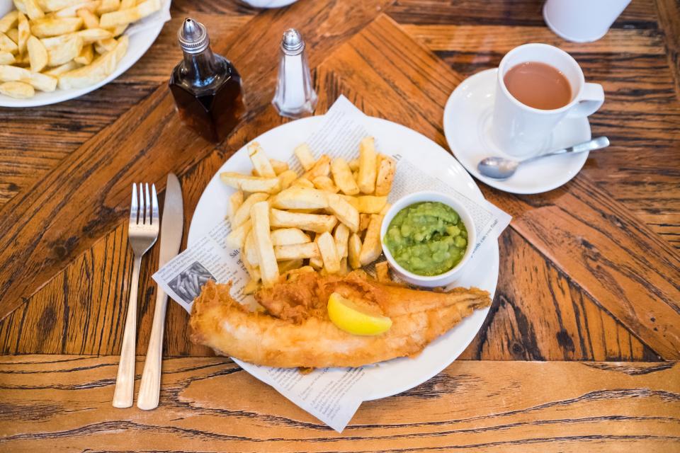 Plate of fish and chips with mushy peas and a cup of tea.