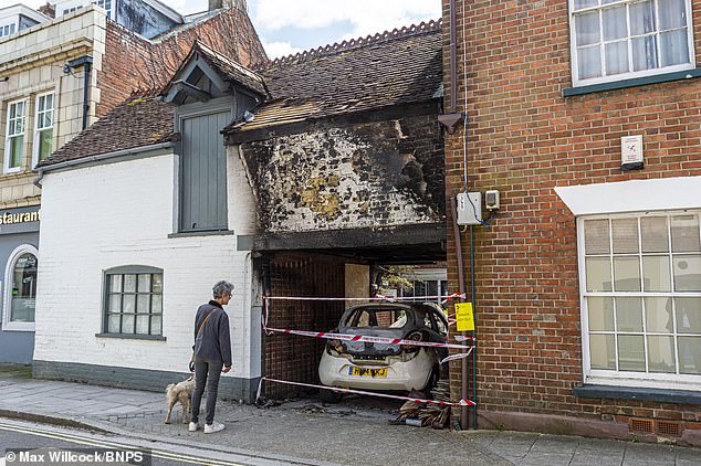 A woman looks at a burned out Ford Ka in the porch of the courtyard after the car fires in Wimborne