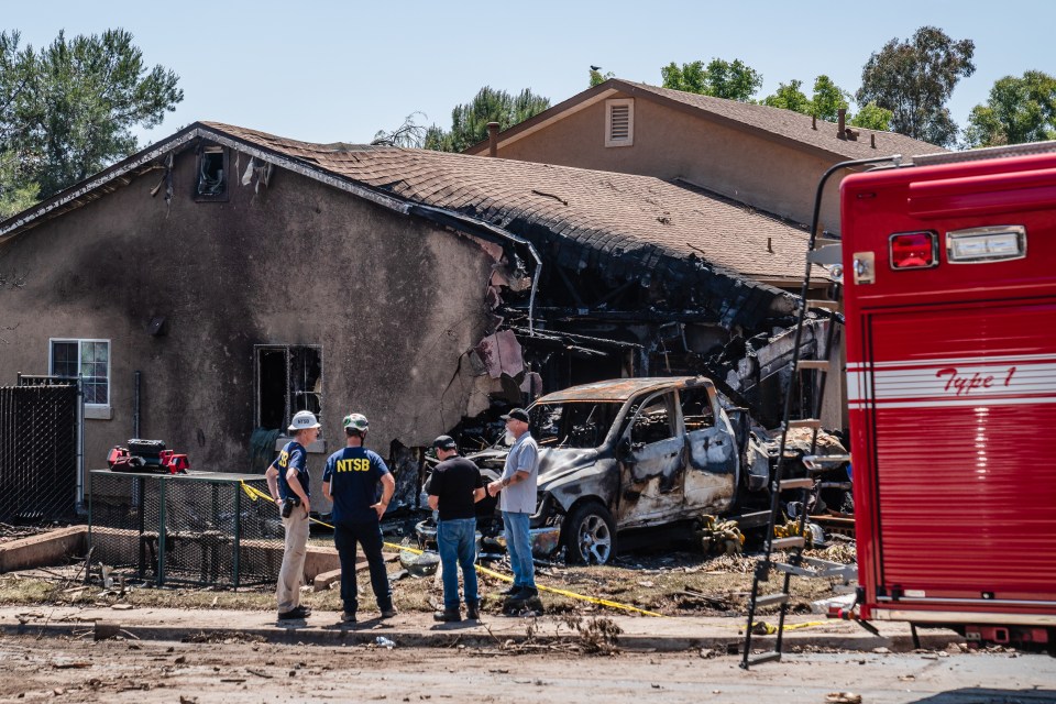 NTSB and FAA investigators at the site of a plane crash that damaged a home and vehicle.