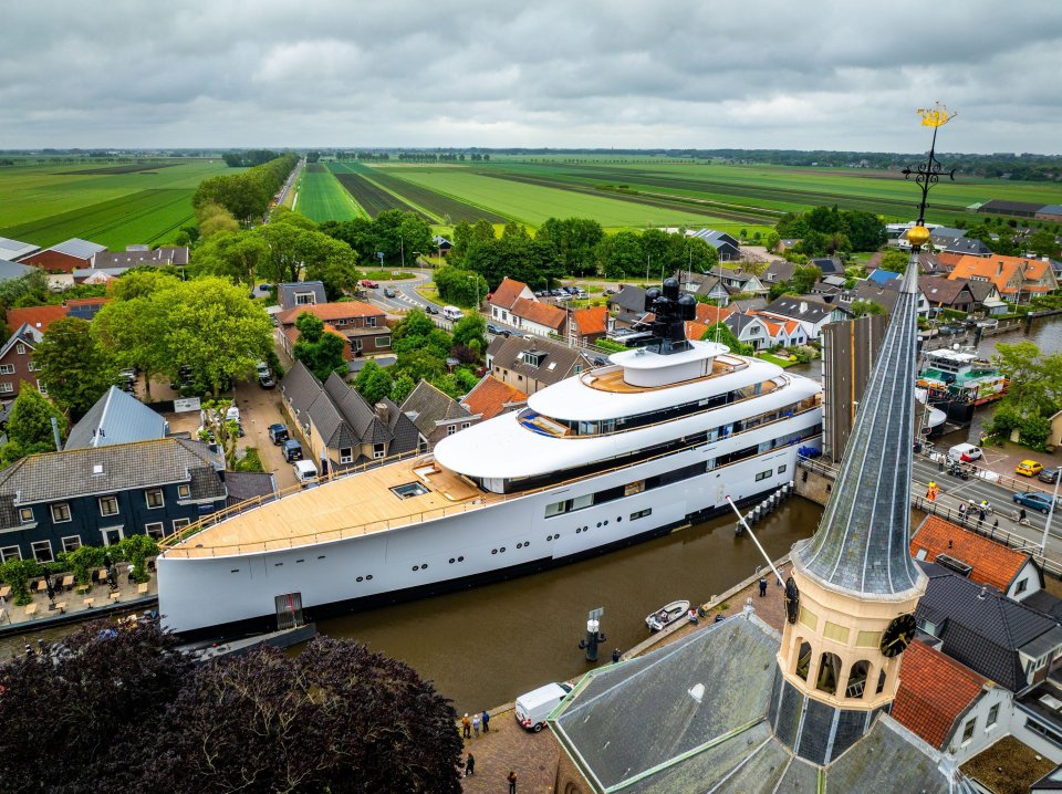 Aerial view of a large yacht passing through a canal in a Dutch town.