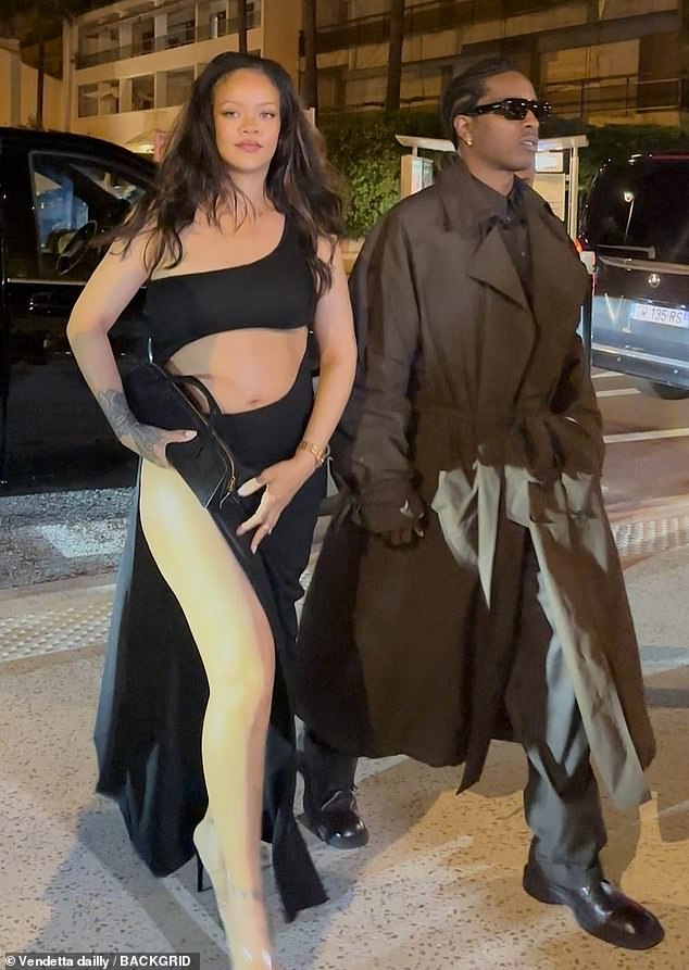 By her side A$AP looked smart in a long brown coat and shades