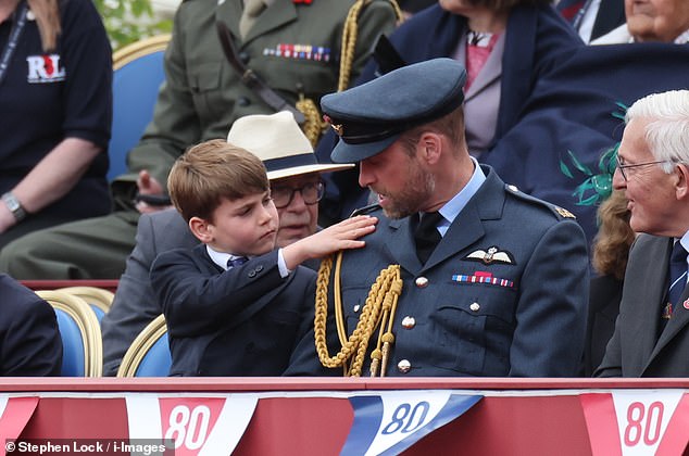 Prince Louis was quick to help out his father Prince William as he brushed down the future King's military uniform at the VE Day celebration at Buckingham Palace today