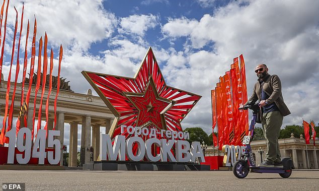 A man rides a scooter in front of a star and inscription reading '1945 Hero City Moscow 2025' installed to mark the upcoming Victory Day in Moscow, Russia