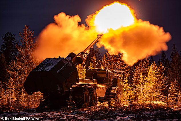 A muzzle flash lights up pine trees as the British Army's Archer Mobile Howitzer gun fires during training near Rovaniemi in the Arctic Circle, Finland, in November