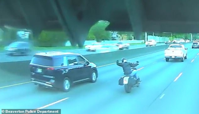 In the shocking clip, the driver of a blue minivan and the motorcyclist are seen traveling side-by-side when the biker appears to gesture at the driver in frustration.