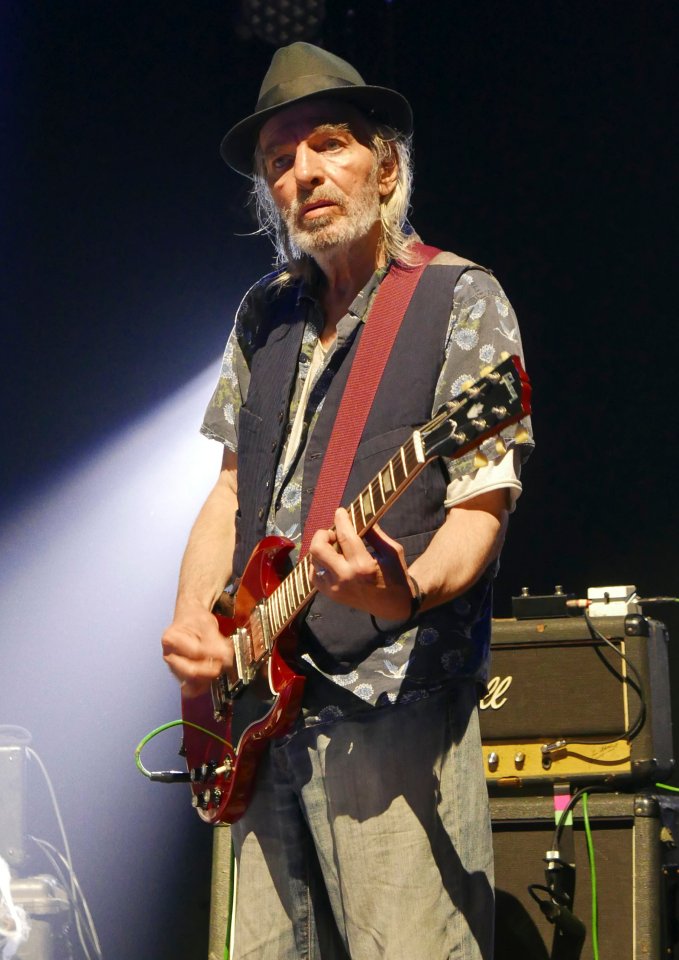 Brian James of The Damned performing on stage with a guitar.