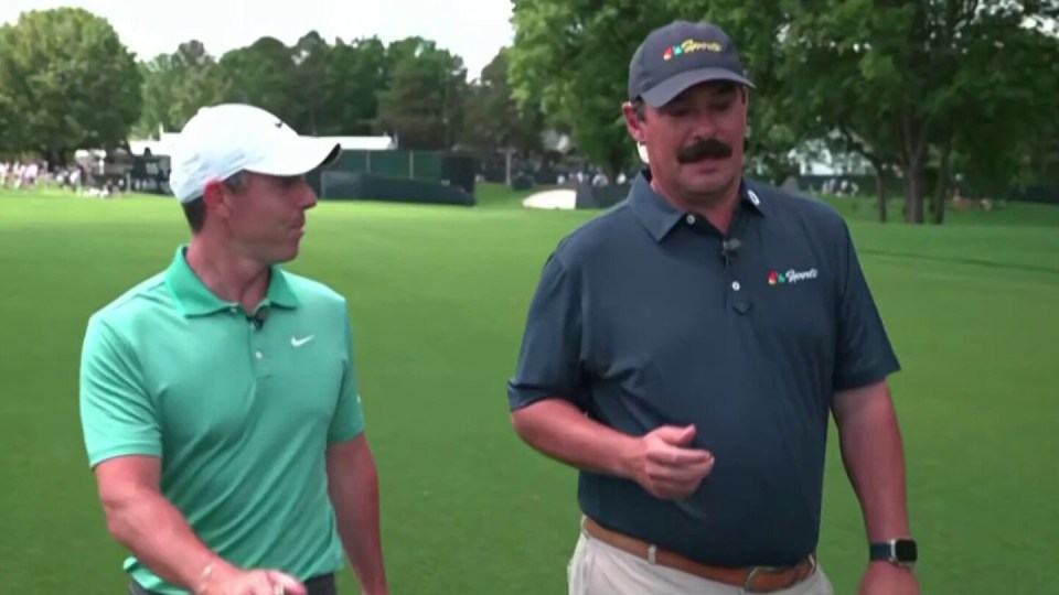 Two men walking and talking on a golf course.