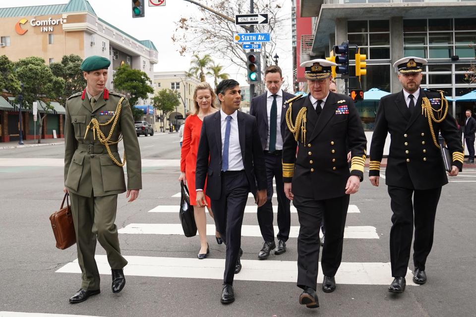 Prime Minister Rishi Sunak and military officials crossing a street.