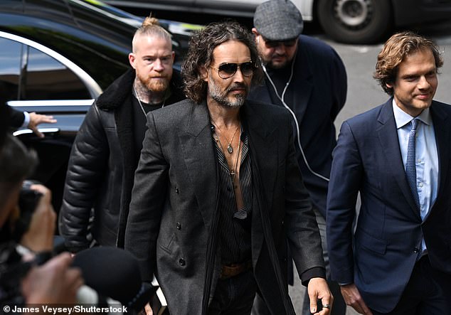 Russell Brand, pictured arriving at Southwark Crown Court this morning, flanked by lawyer Oliver Schneider-Sikorsky (right)