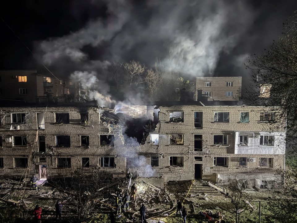 Apartment building damaged by a drone strike at night.