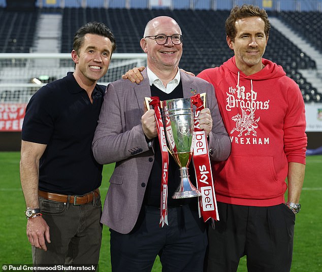 Wrexham co-owners Rob McElhenney (left) and Ryan Reynolds (right) celebrate promotion from League One with director Shaun Harvey. A win against Charlton last week secured their second place finish