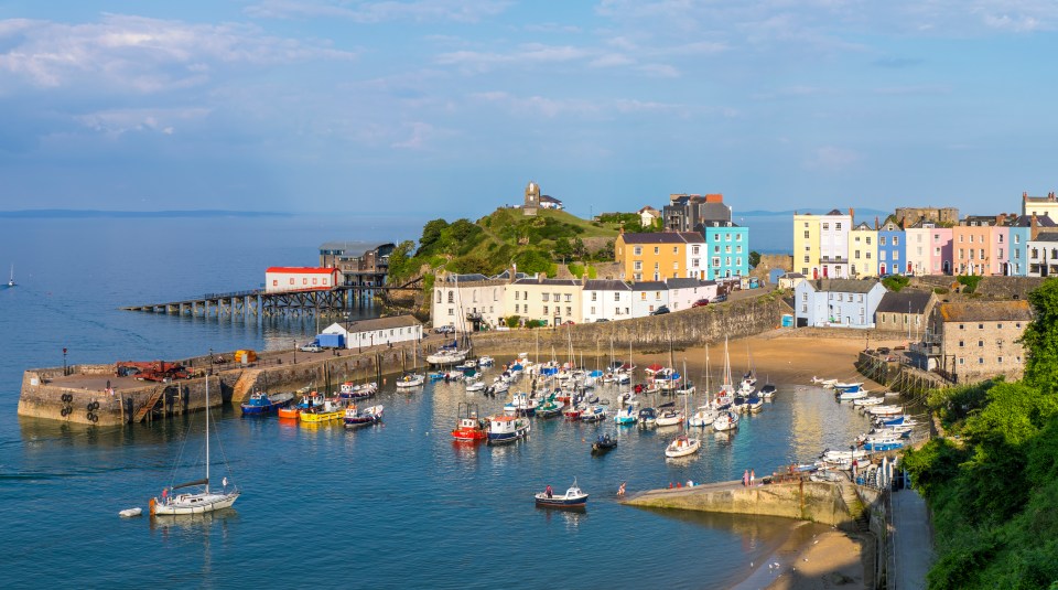 Tenby harbor in Pembrokeshire, Wales, with colorful buildings and many boats.