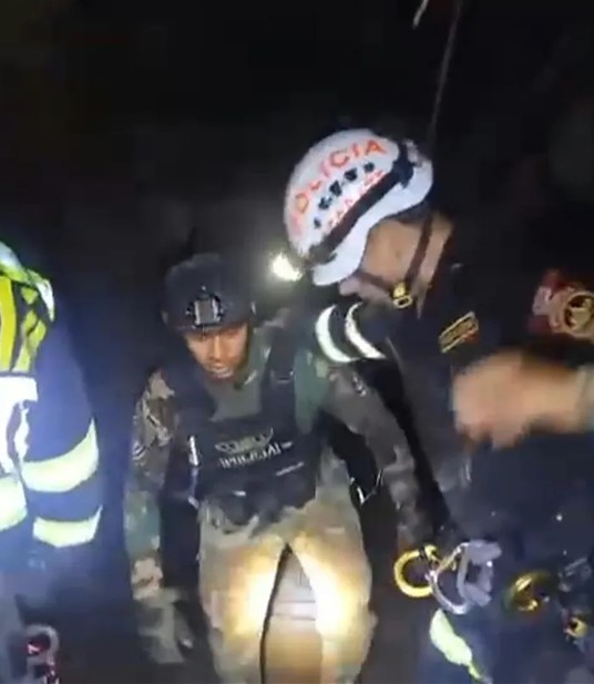 Security personnel assisting a person in a dark setting.
