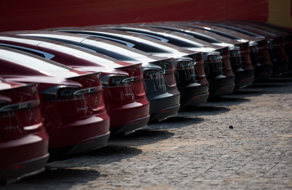 Row of Tesla Model S cars in a dealership parking lot.
