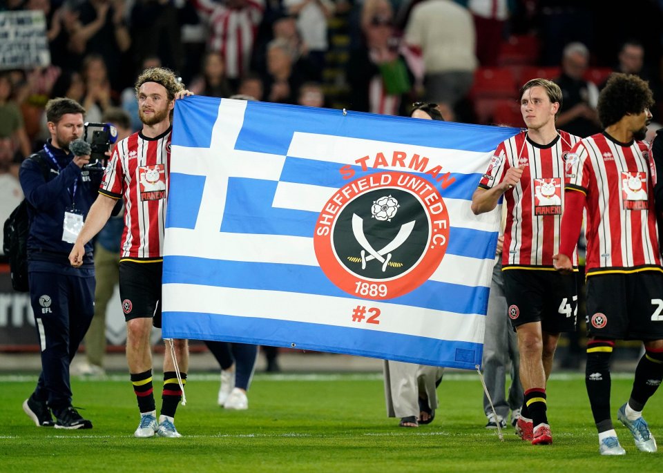 Sheffield United players holding a flag in memory of former player George Baldock.