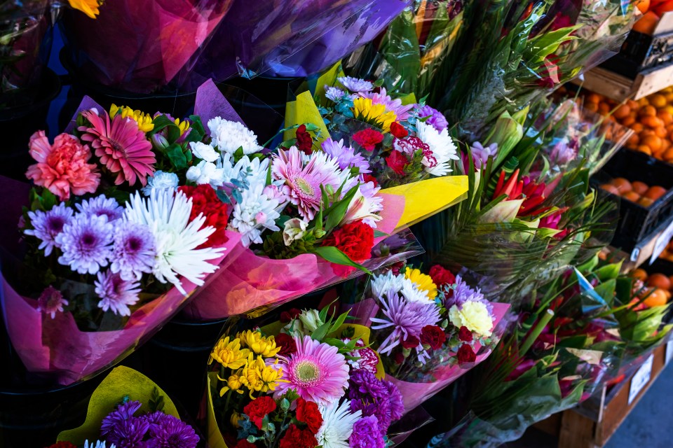 Several bouquets of colorful fresh-cut flowers wrapped in cellophane.