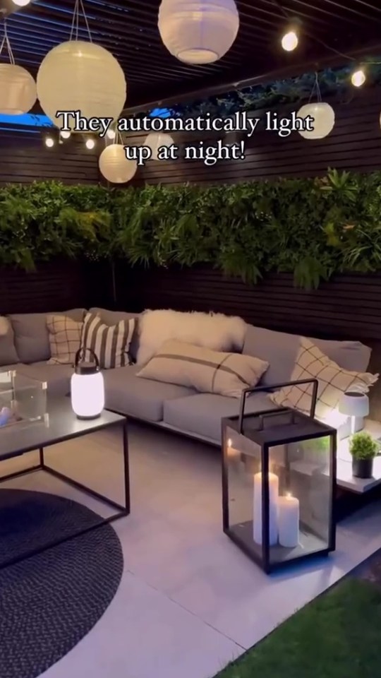 Nighttime view of a patio with a sectional sofa, lanterns, and string lights.