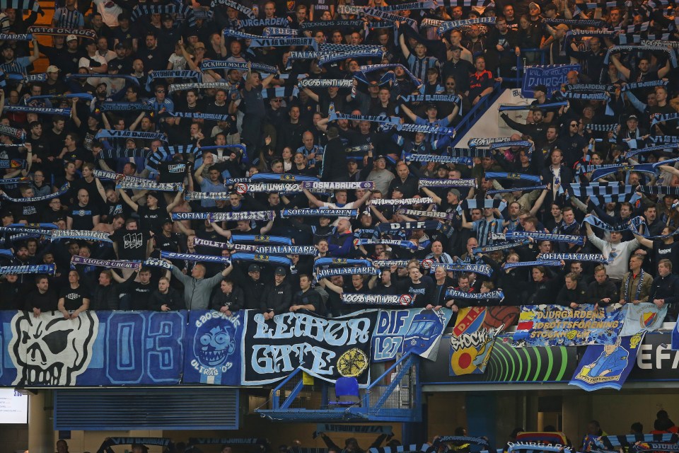 Djurgården supporters holding scarves at a soccer match.