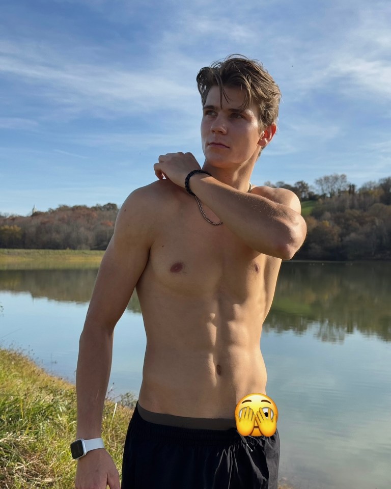 Shirtless young man standing by a lake.