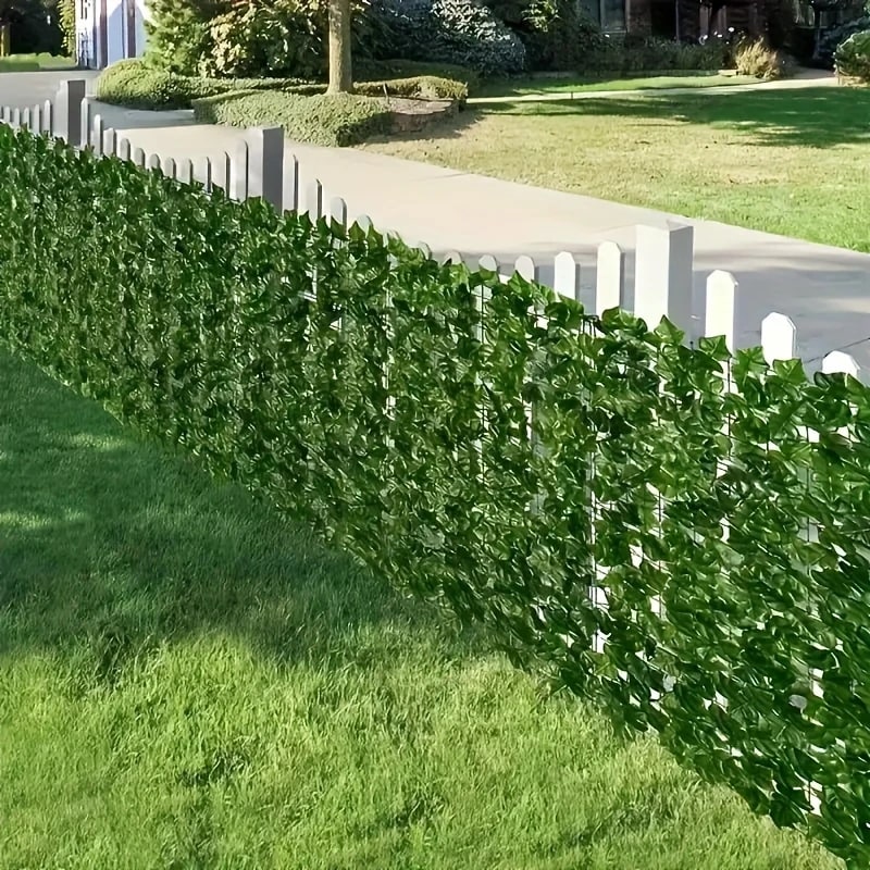 Artificial ivy covering a white picket fence.