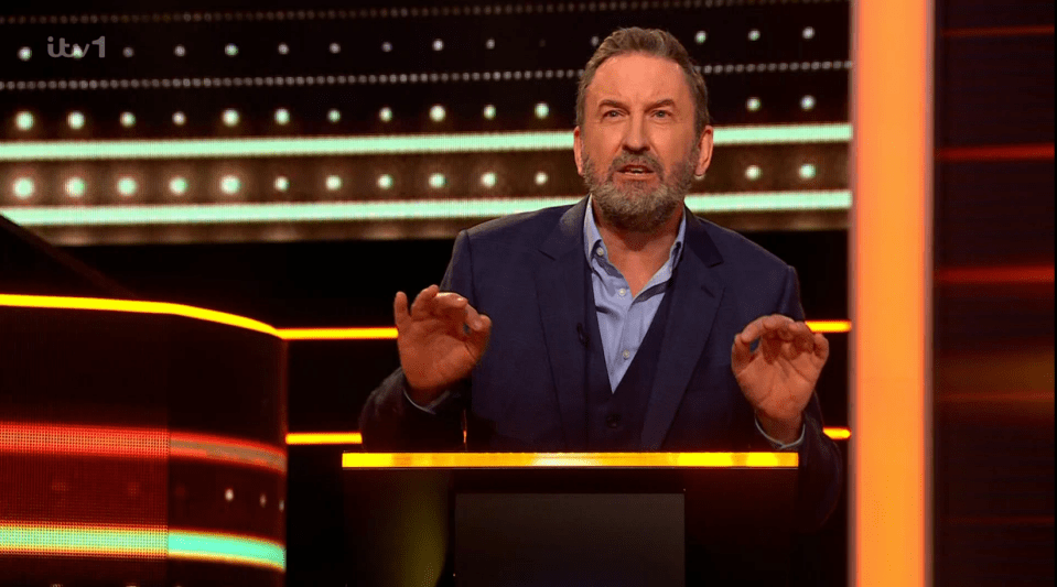 Man gesturing at a game show podium.