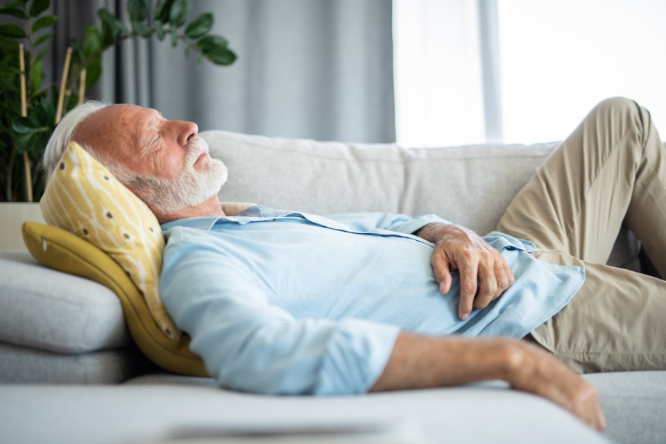 Senior man napping on a sofa.