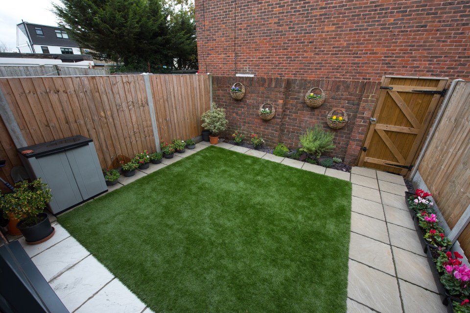 Small backyard with artificial turf, potted plants, and wooden fence.