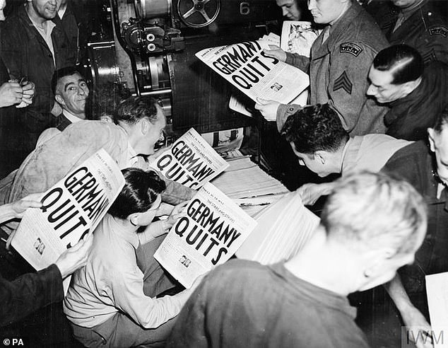 Pictured: Soldiers pulling copies of 'Stars and Stripes' from the press of the London Times with the headline reading 'Germany Quits'