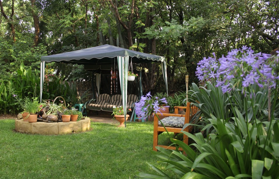 African garden with gazebo, swing chair, and flowers.
