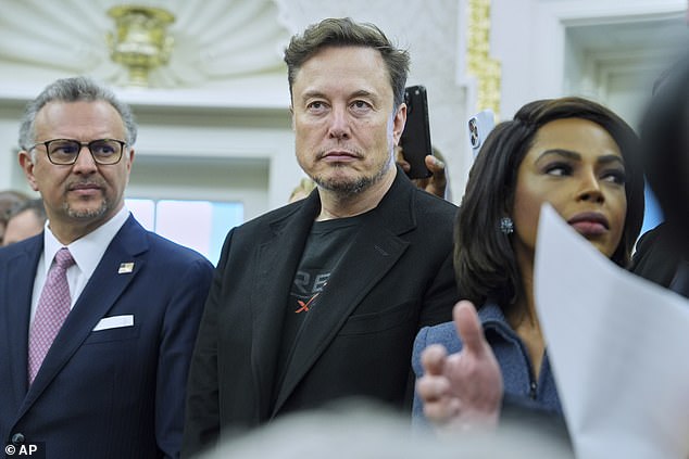 South African-born Elon Musk stands silently in the Oval Office amongst the press as President Donald Trump humiliated the president of his birth nation