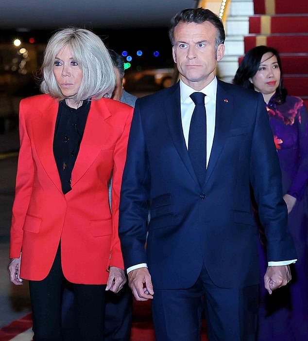 The French President appeared to ball one of his hands into a fist as he stepped onto the tarmac in Vietnam alongside his wife