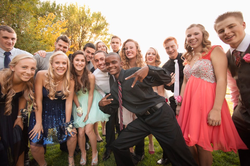 Large group of smiling teenagers in prom attire.