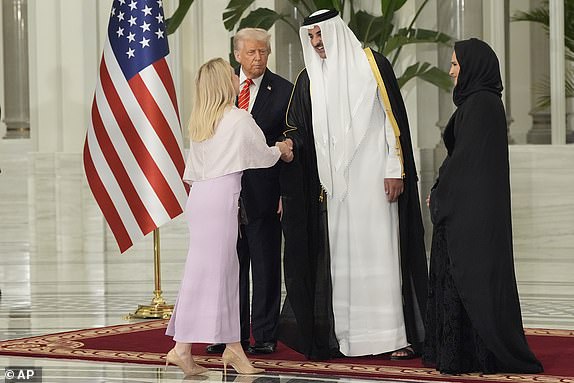 President Donald Trump looks toward Qatar's Emir Sheikh Tamim bin Hamad Al Thani as the emir shakes hands with White House Press Secretary Karoline Leavitt before a state dinner at Lusail Palace in Doha, Qatar, Wednesday, May 14, 2025. (AP Photo/Alex Brandon)