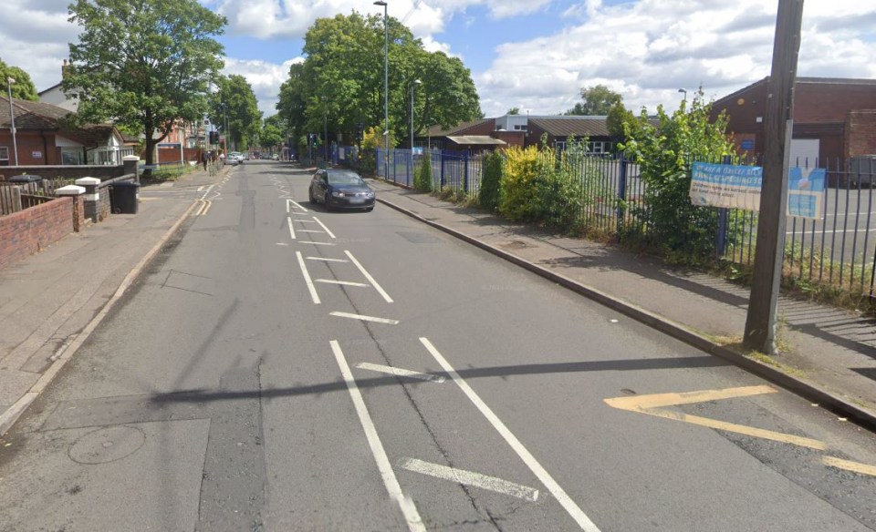 Street scene with a car driving past a school.