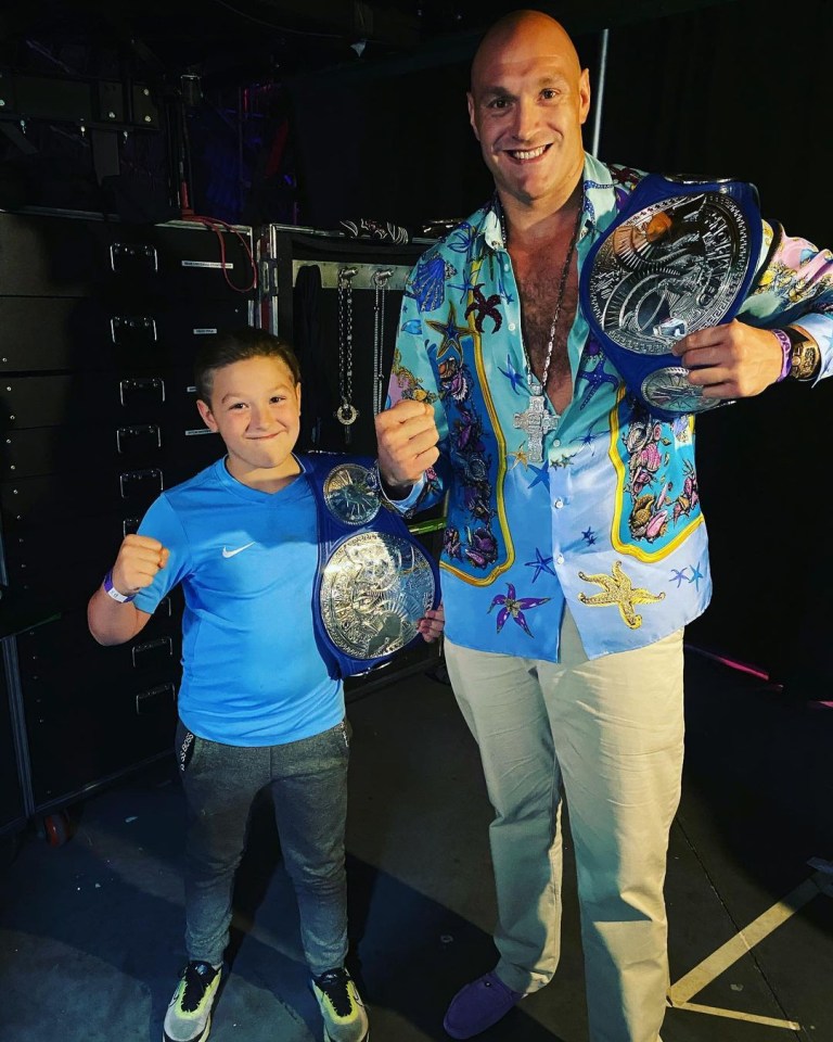 Tyson Fury's son, Prince John James, poses with Vince McMahon holding wrestling championship belts.