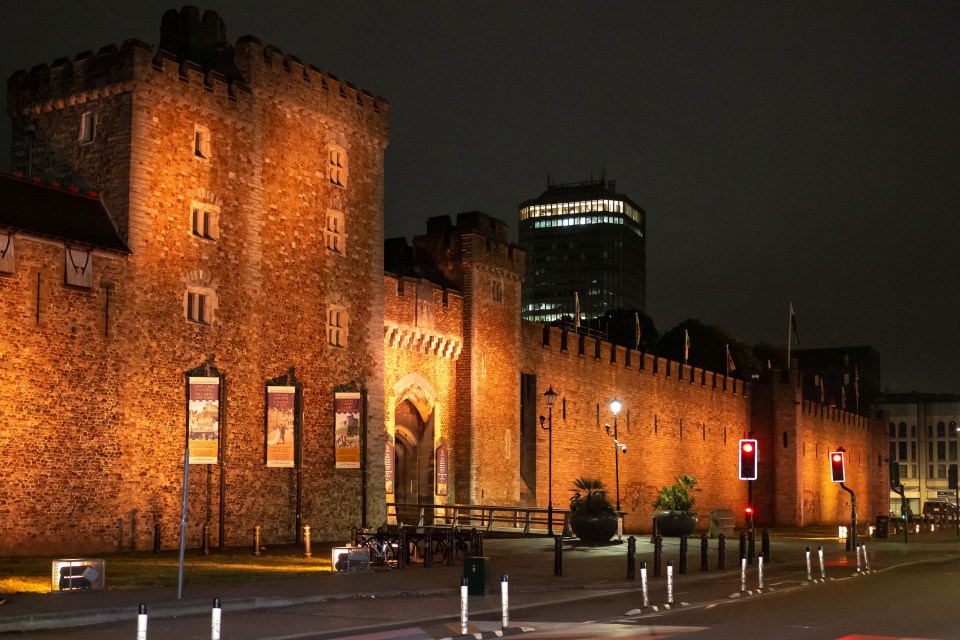 Cardiff Castle lit orange at night.