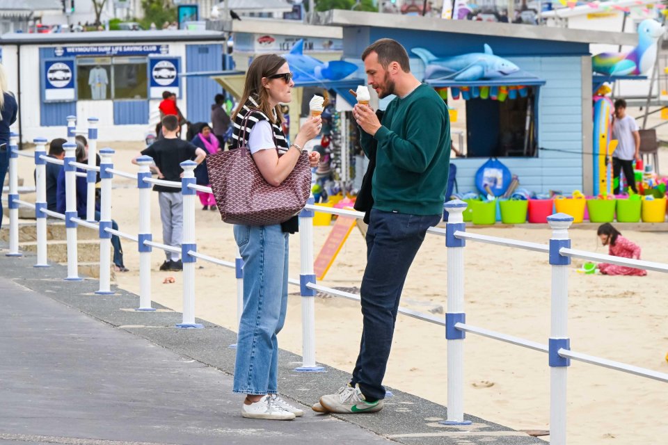 Couple eating ice cream on a seaside promenade.