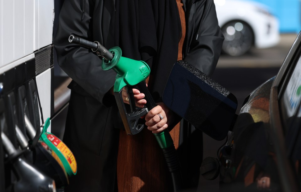 Person pumping petrol into a car.