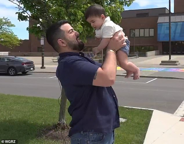Jean Paul Al Arab's celebratory walk across stage during his graduation last week at University at Buffalo descended into chaos when police began trailing and chasing him - all because he was proudly holding his infant baby son while accepting his diploma (pictured: Al Arab and his son)