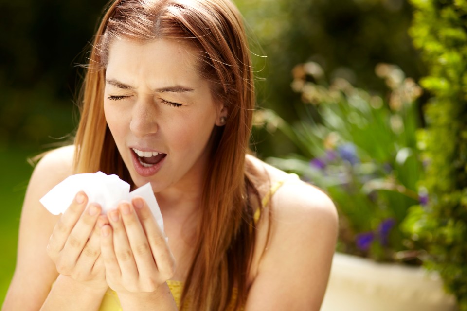 Woman sneezing into a tissue.