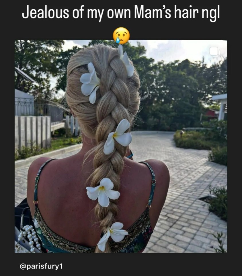 Woman's long blonde braid adorned with white flowers.