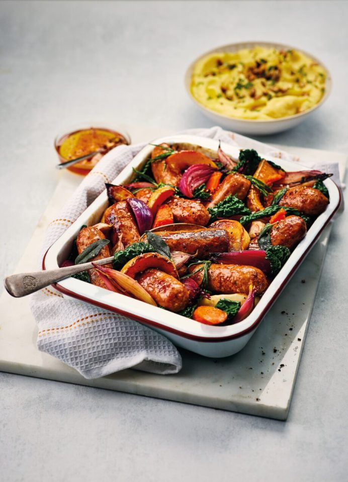 Roast sausages with vegetables in a baking dish.