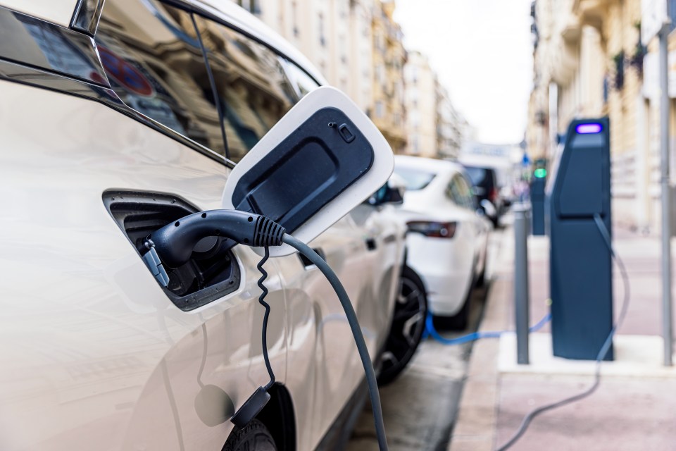 Electric car charging at a city street charging station.