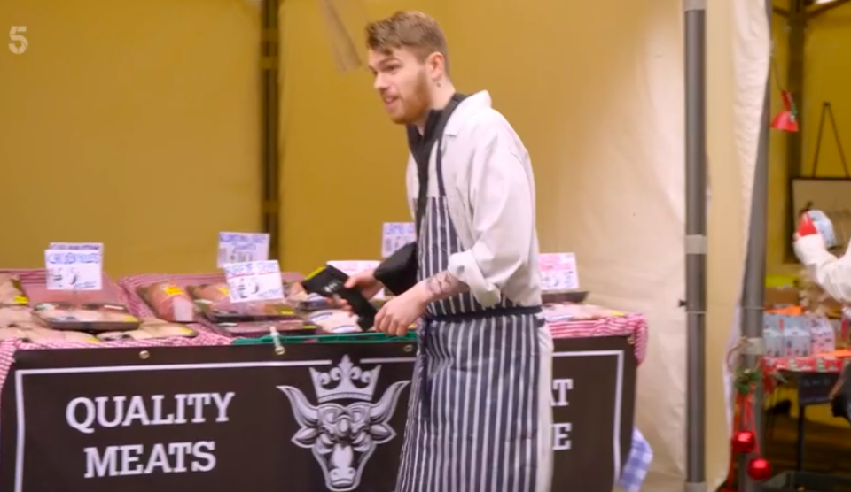 A butcher at a market stall using a card reader.