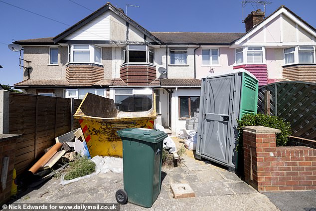 The driveway next to the Browns' house is filled with rubbish and a skip, as well as a recent addition of a portable toilet