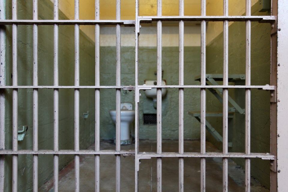 Alcatraz prison cell interior viewed through bars.