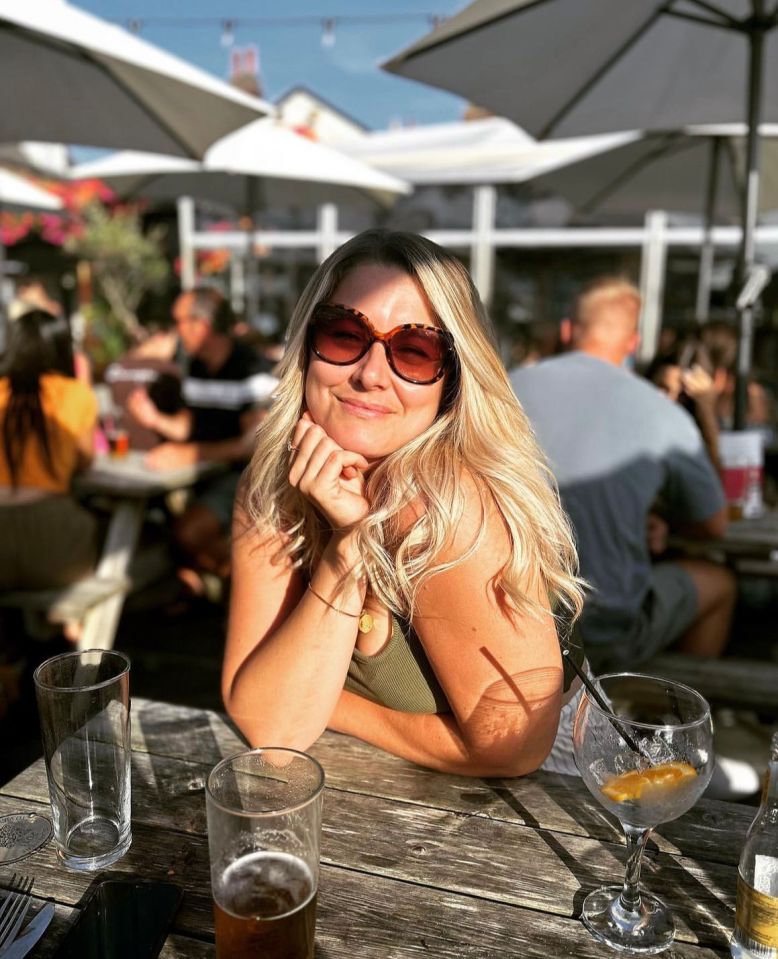 Woman sitting at an outdoor table wearing sunglasses.